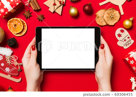 Top view of woman holding tablet in her hands on red background Top view of woman holding tablet in her hands on red background 69306455