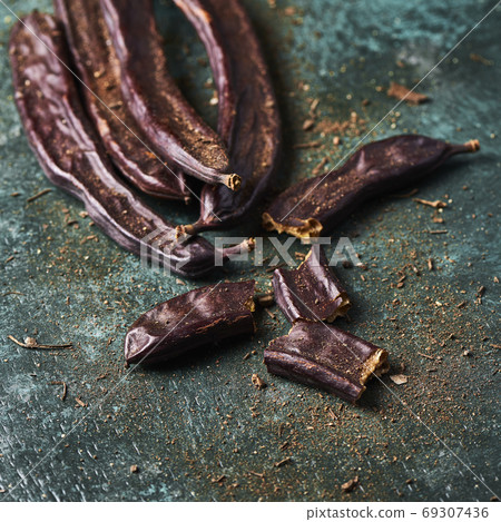 ripe carob beans on a green surface 69307436