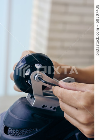 man changing the wheels of an inline skate man changing the wheels of an inline skate 69307439