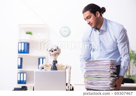 Young male employee and skeleton in the office Young male employee and skeleton in the office 69307467