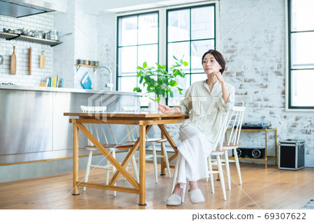 A middle-aged woman relaxing at the dining room 69307622