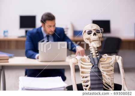 Young male employee with skeletons in the office 69308082