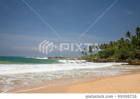 Tropical paradise with trees on beach against blue sky with clo 69308716