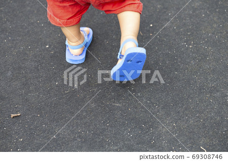 Foot of child walking and blue beach sandals and black back and copy space 69308746