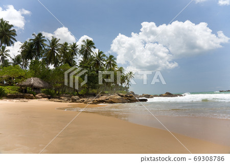 Tropical paradise with trees and house on beach against blue sk Tropical paradise with trees and house on beach against blue sk 69308786