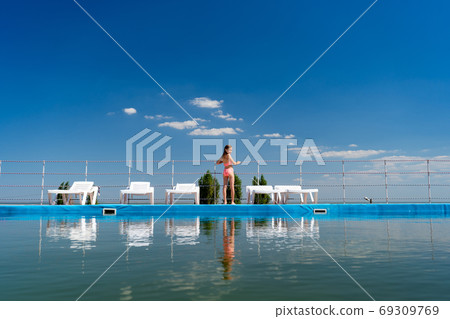 rear view. girl in swimsuit between sun loungers rear view. girl in swimsuit between sun loungers 69309769