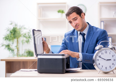 Young male employee making copies at copying machine Young male employee making copies at copying machine 69309838