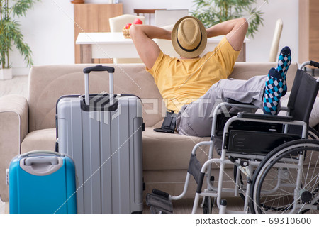Young man in wheel-chair preparing for departure at home Young man in wheel-chair preparing for departure at home 69310600