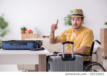 Young man in wheel-chair preparing for departure at home Young man in wheel-chair preparing for departure at home 69310601
