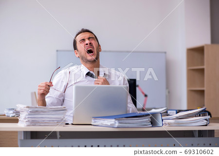 Young male employee unhappy with excessive work Young male employee unhappy with excessive work 69310602