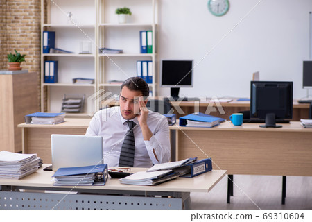 Young male employee unhappy with excessive work Young male employee unhappy with excessive work 69310604