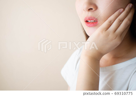 Young woman suffering from toothache over white background. Cause of tooth pain include tooth decay, inflammation, dental abscess, gum disease or sensitive teeth. Dental health concept. 69310775