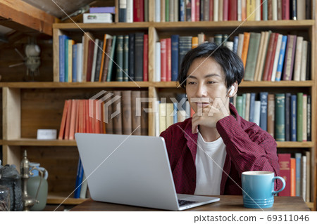 A young man working on a computer with wireless headphones A young man working on a computer with wireless headphones 69311046