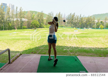 Asian golfer woman swing golf ball practice at golf driving rang 69311544