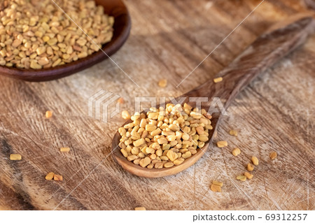 Fenugreek seeds on a wooden spoon Fenugreek seeds on a wooden spoon 69312257