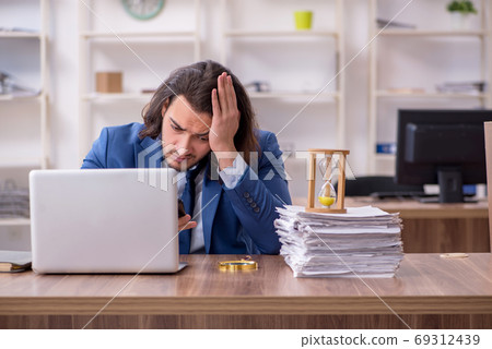 Young male employee unhappy with excessive work 69312439