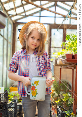 Adorable small girl kid in hat watering seedlings Adorable small girl kid in hat watering seedlings 69314089