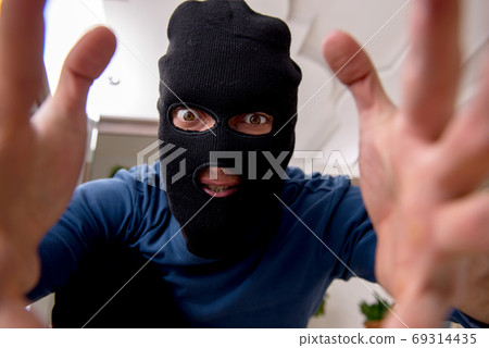 Male robber stealing valuable things from the house 69314435