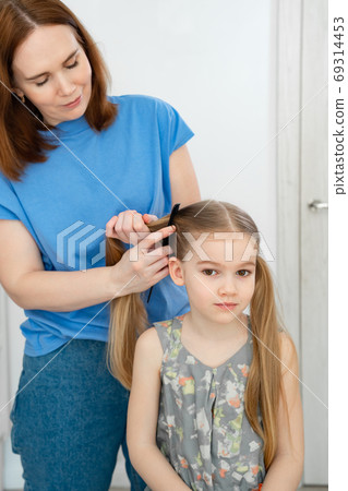 mom makes ponytails of her little daughter mom makes ponytails of her little daughter 69314453