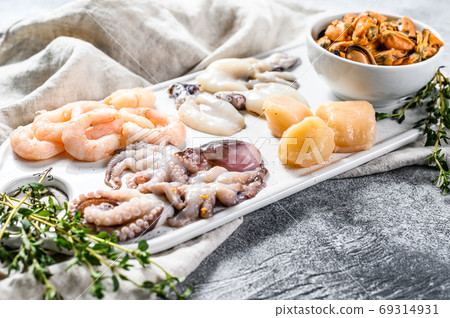 Raw seafood mix on a ceramic chopping Board. Gray background. Top view. 69314931