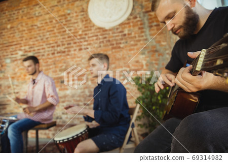 Musician band jamming together in art workplace with instruments Musician band jamming together in art workplace with instruments 69314982