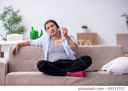 Young male alcoholic drinking wine at home 69315501