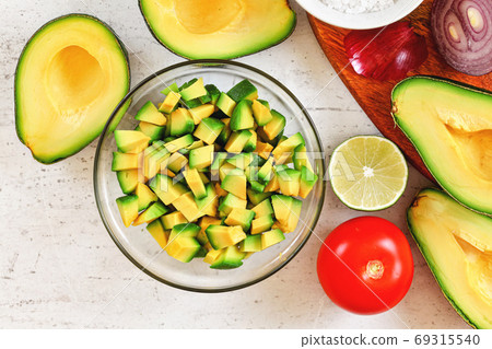 Avocado halves, limes tomato and onion - basic guacamole ingredients on white working board, view from above Avocado halves, limes tomato and onion - basic guacamole ingredients on white working board, view from above 69315540