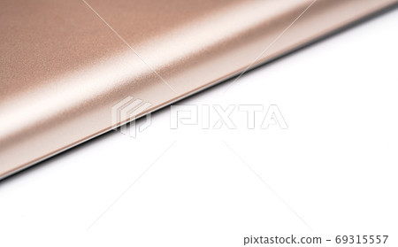 Rose gold colored metal smartphone case, closeup macro detail forming diagonal line with space for text right, abstract technology background Rose gold colored metal smartphone case, closeup macro detail forming diagonal line with space for text right, abstract technology background 69315557
