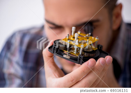 Young male watchmaker working in the workshop Young male watchmaker working in the workshop 69316131