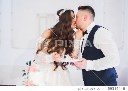 Beautiful bride and groom embracing and kissing on their wedding day 69316446