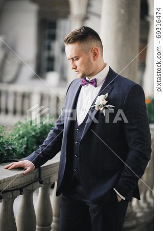Happy handsome smiling groom posing with boutonniere 69316474