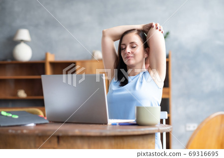 Business woman stretches her body doing yoga exercise at coffee break. 69316695