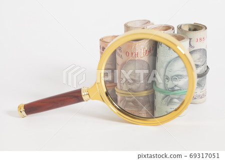 Rolls of Indian Currency Rupee Notes with magnifying glass Rolls of Indian Currency Rupee Notes with magnifying glass 69317051