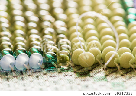 Embroiders with colorful beads. Close-up Embroiders with colorful beads. Close-up 69317335