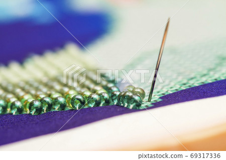 Embroiders with colorful beads. Close-up 69317336