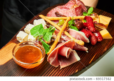 Assorted cheeses and meat delicacies on wooden Assorted cheeses and meat delicacies on wooden 69317382