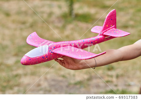 Girl launching a pink toy plane into the air Girl launching a pink toy plane into the air 69317383