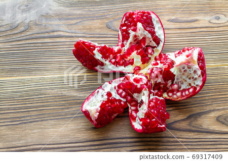 Open fresh ripe pomegranate on brown wooden Open fresh ripe pomegranate on brown wooden 69317409