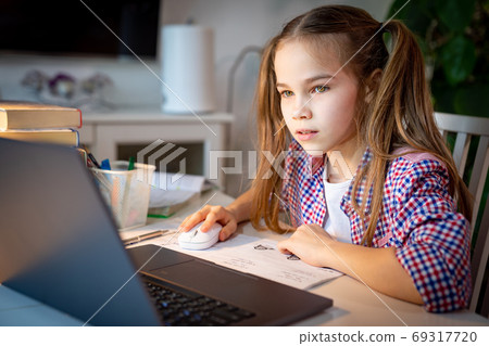 schoolgirl makes lessons, homework on laptop. 69317720