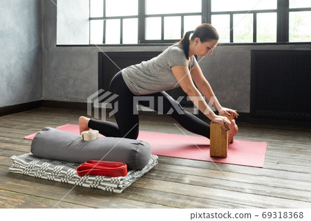 woman doing stretching exercise using props, block, Ardha Hanumanasana woman doing stretching exercise using props, block, Ardha Hanumanasana 69318368
