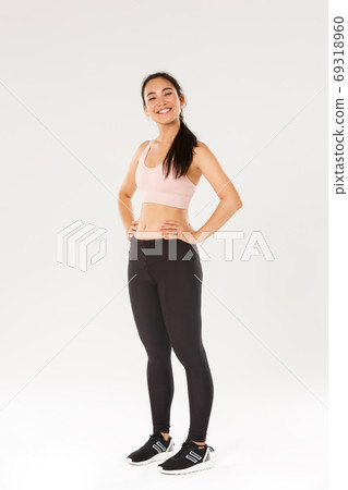 Full length of proud and happy female athlete in sportswear looking happy and accomplished, fitness girl gaining her sports goal, looking delighted, workout in gym, white background 69318960