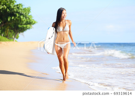 Surfer woman in bikini on beach on Hawaii. Surfboard woman walking in beach water with boogieboard 69319614
