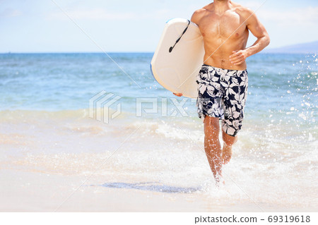 Beach fun surfer man running with body board. Fit fitness model doing water sport bodyboarding surfing. Photo from Kaanapali beach, Maui, Hawaii 69319618