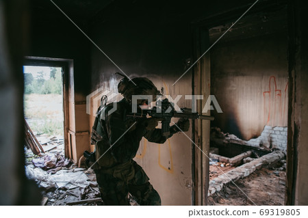 Soldier in full US MARSOC equipment entering abandoned building, aiming different angles with MK18 assault rifle Soldier in full US MARSOC equipment entering abandoned building, aiming different angles with MK18 assault rifle 69319805