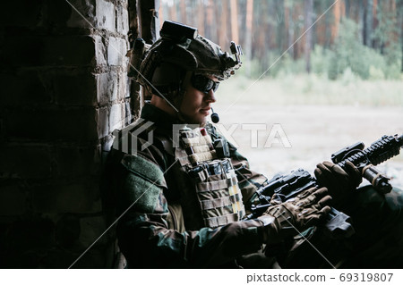 Weapon inspection while waiting on a spot. Military man checks his assault rifle preparing for operation. Weapon inspection while waiting on a spot. Military man checks his assault rifle preparing for operation. 69319807