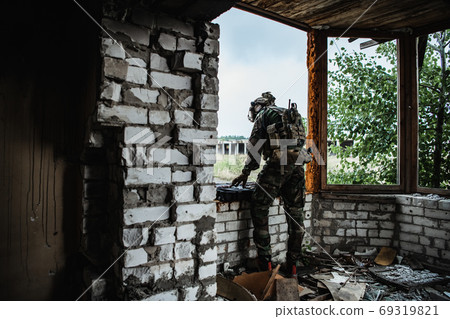 Military man preparing equipment of firearms to the mission. Pulls out assault rifle from the ammunition case. Military man preparing equipment of firearms to the mission. Pulls out assault rifle from the ammunition case. 69319821