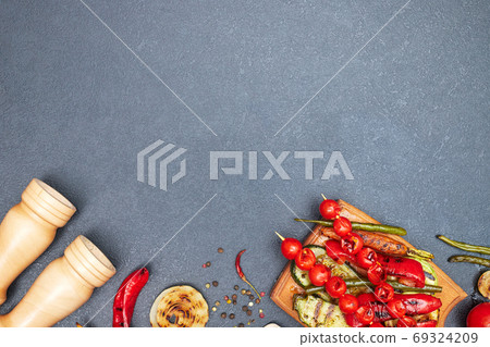 grilled vegetables on a wooden board on a black table, copyspace, top view 69324209