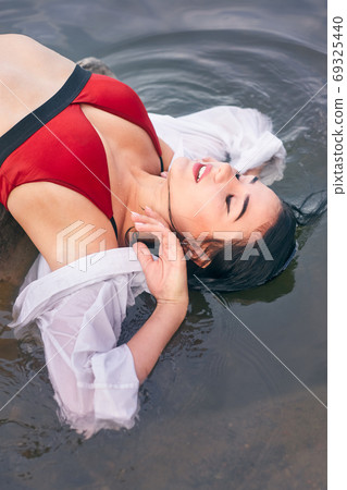 girl in the river on a stone in a red swimsuit one girl in the river on a stone in a red swimsuit one 69325440