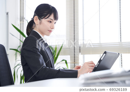日本女性商業女性,在辦公室使用平板電腦將紙質材料轉換為數據 日本女性商業女性,在辦公室使用平板電腦將紙質材料轉換為數據 69326189