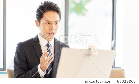 A man making a video call to a PC 69328803